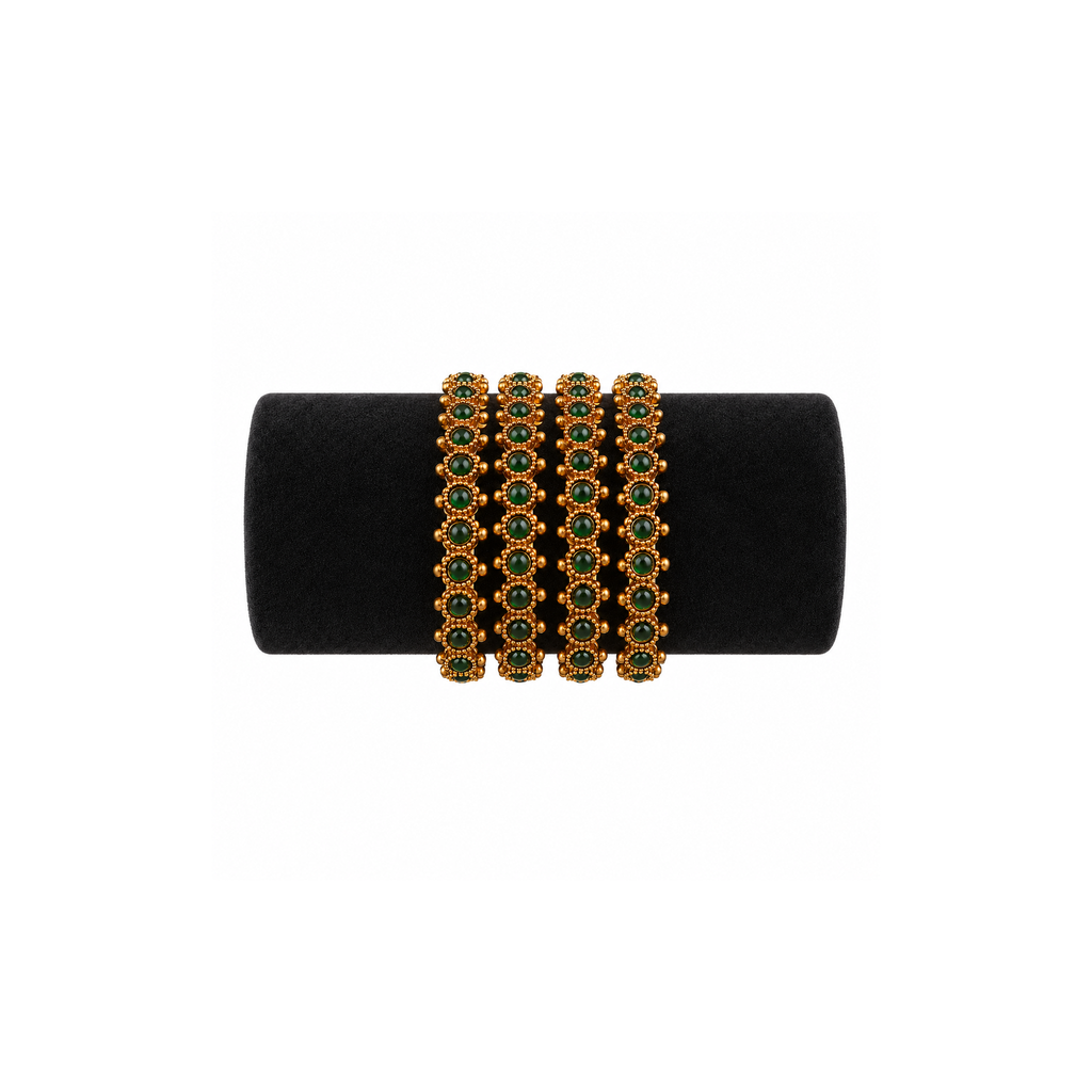 Four antique gold-tone bangles with oval deep-green stones on black velvet