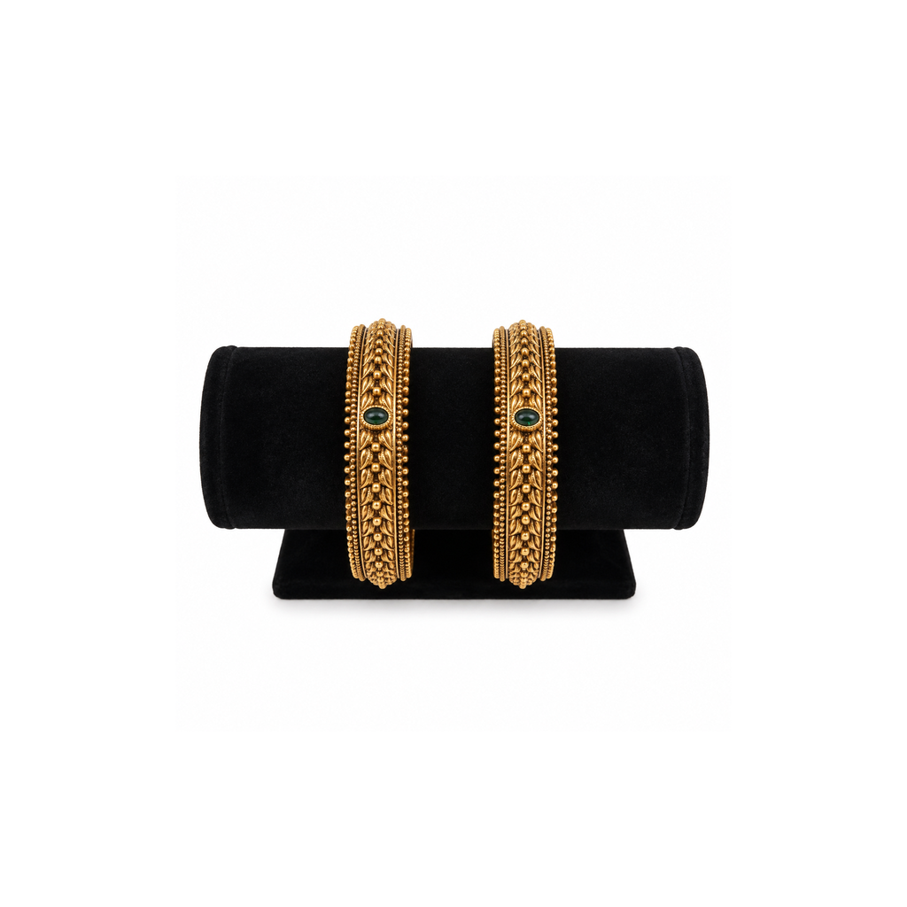 Two green stone braided antique gold-tone bangles on black velvet