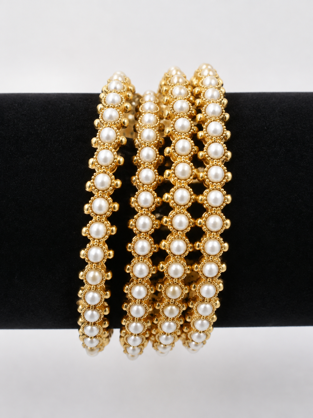 Four gold-tone bangles with creamy pearl-style rows, front view