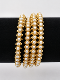 Four gold-tone bangles with creamy pearl-style rows, front view