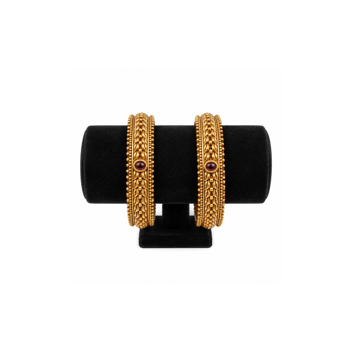 Two red stone braided antique gold-tone bangles on black velvet