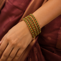 Indian woman wearing four green stone antique gold-tone bangles