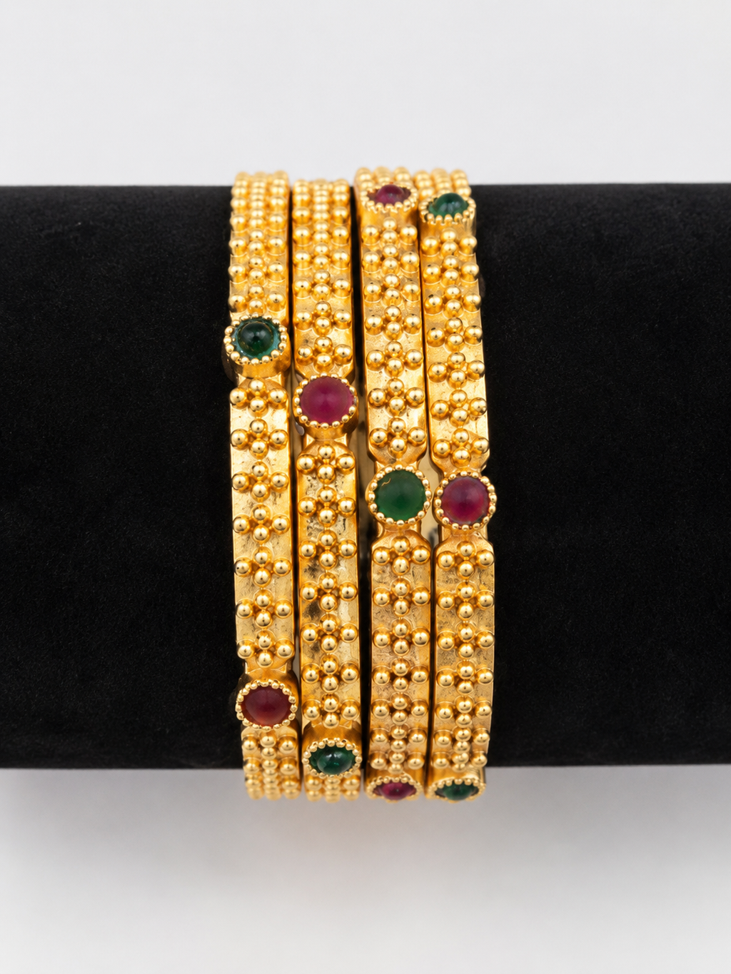Red and green accent gold-tone bangle set, front view
