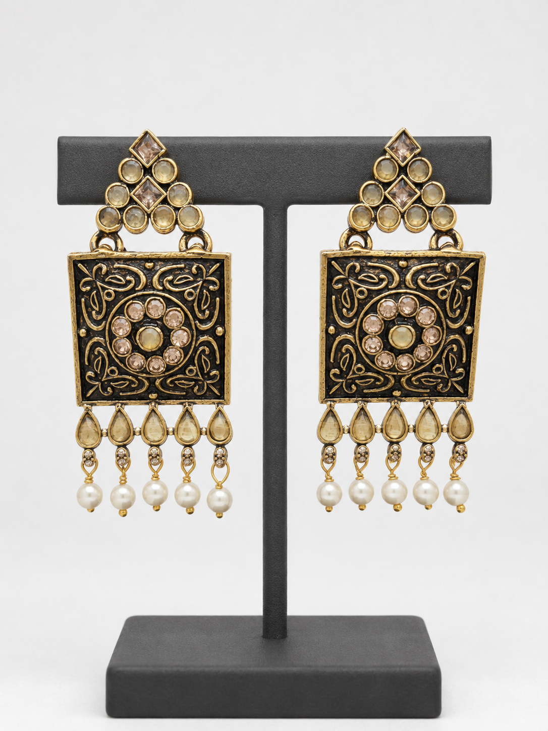 Close view of engraved square earrings with champagne accents