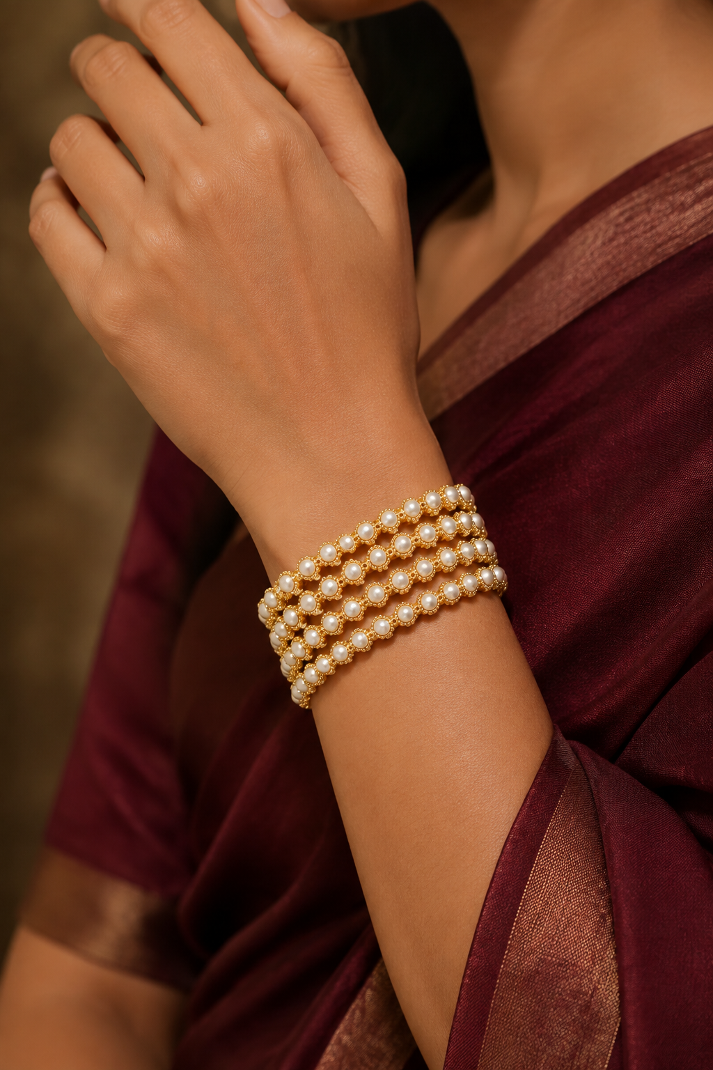 Four pearl-style gold-tone bangles worn with maroon silk