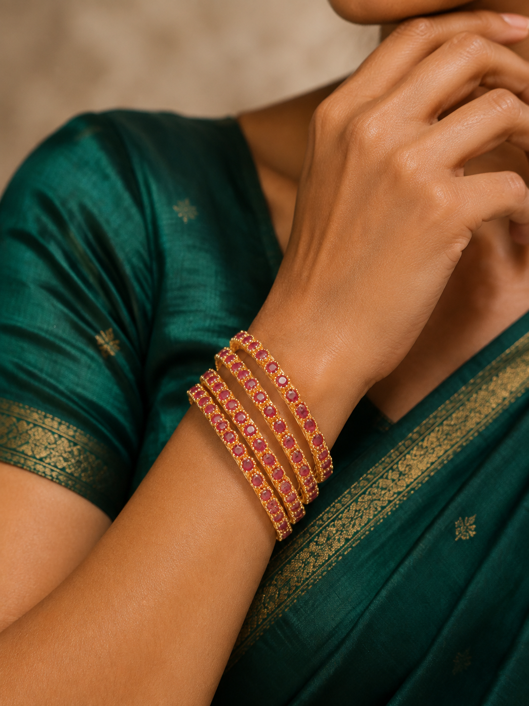 Four ruby-pink gold-tone bangles worn with green silk